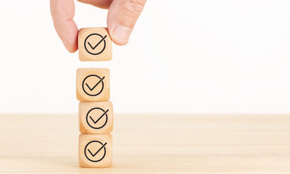 Checking or checklist concept. Hand picked wooden cube block with check icon stacked on wooden table. Copy space